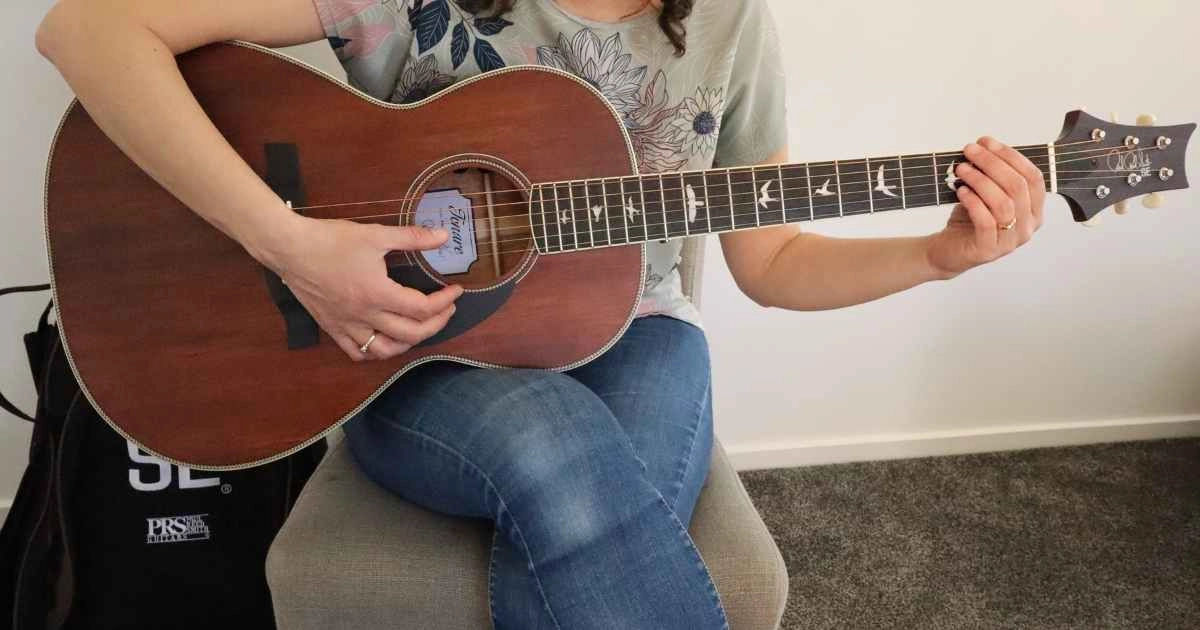 A woman with the PRS Paul Reed Smith SE P20 Parlor Acoustic Guitar