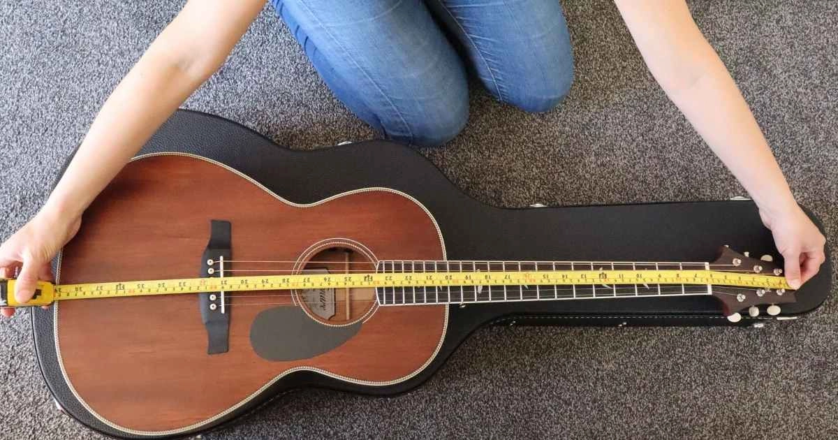 A woman measuring the length of the guitar (headstock to the end of the guitars' body)