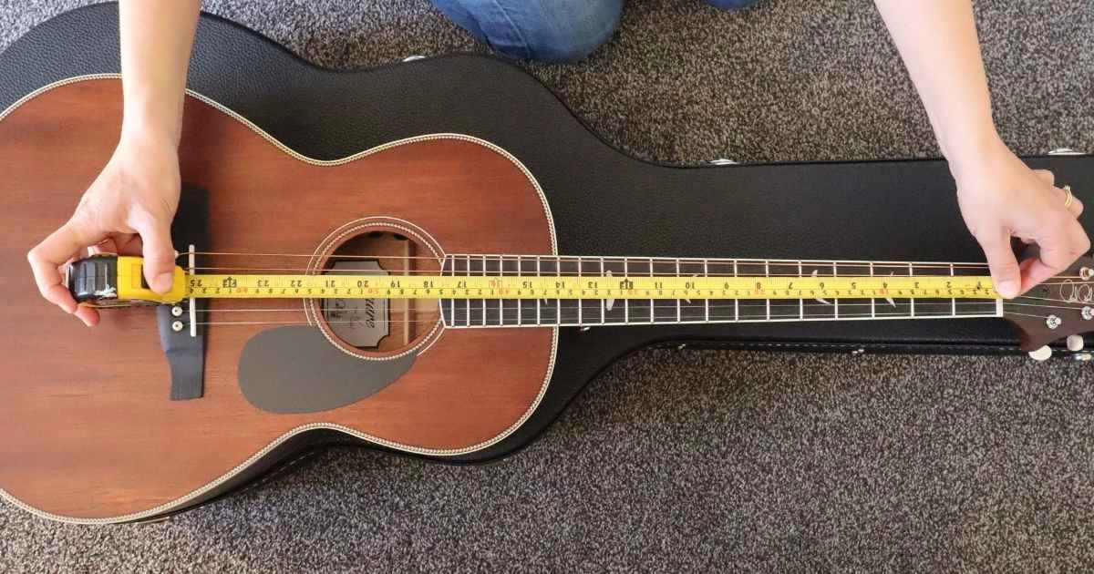 A woman measuring the scale length of an acoustic guitar (from the nut to the bridge)